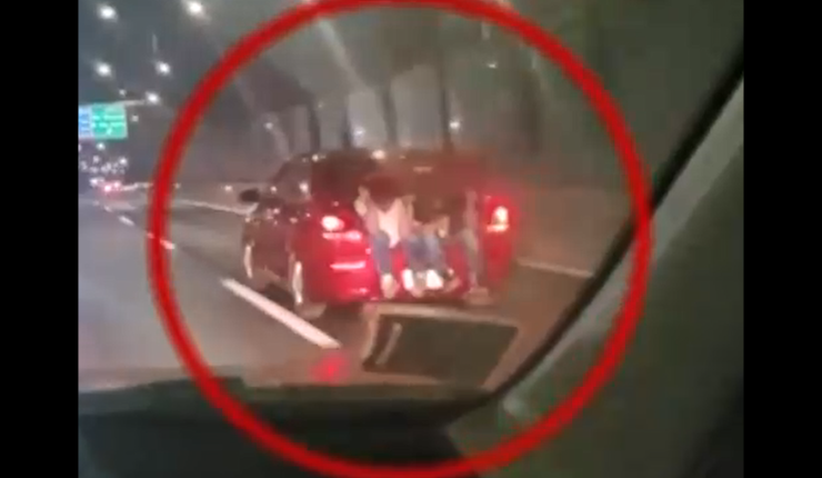 Con los pies colgando: Captan a dos personas viajando sentadas en maletero de auto en plena autopista